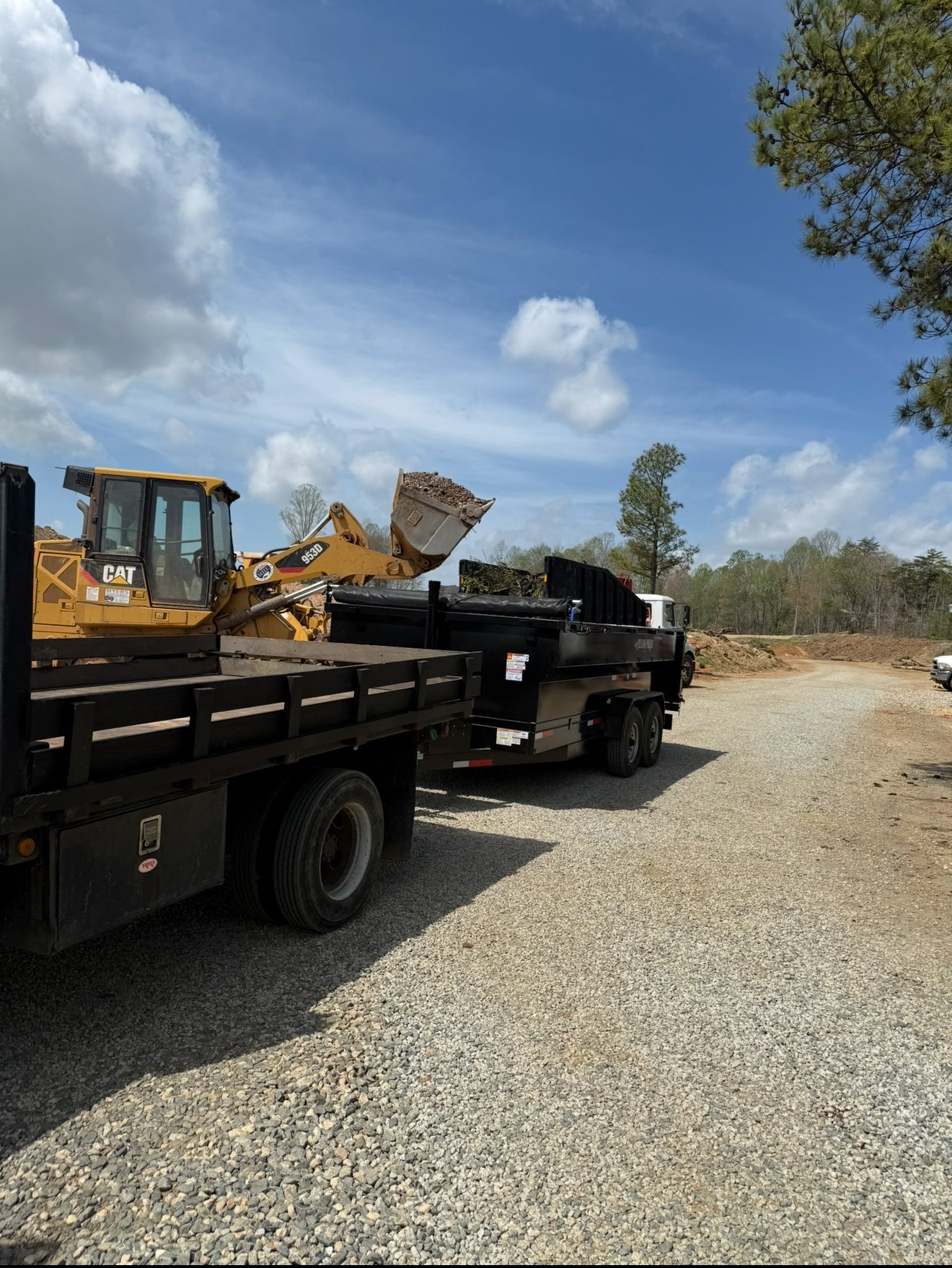 Heavy machinery loading debris into dump trailer — 316 Tree Services